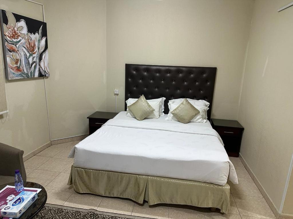 Al Farhan Hotel Suites Al siteen في الجبيل: غرفة نوم بسرير كبير عليها شراشف ووسائد بيضاء