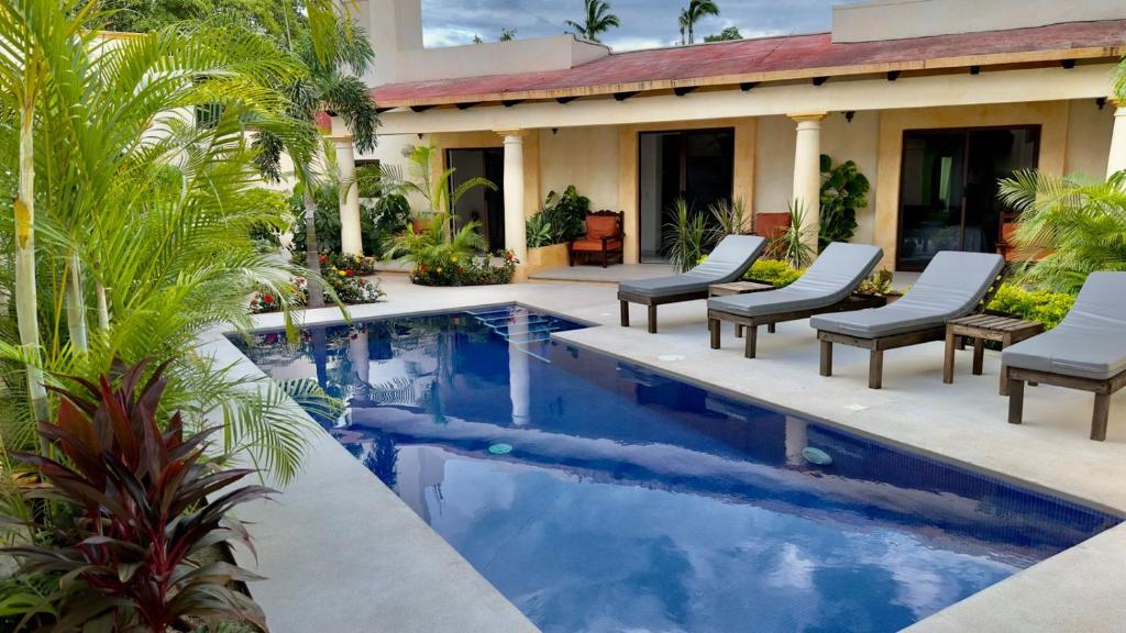a swimming pool with chairs and a house at Casa Puerto Viejo in Puerto Escondido