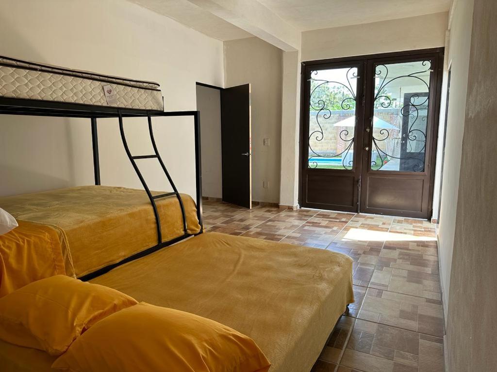 a bedroom with two beds and a glass door at Casa los ventanales in Chiconcuac