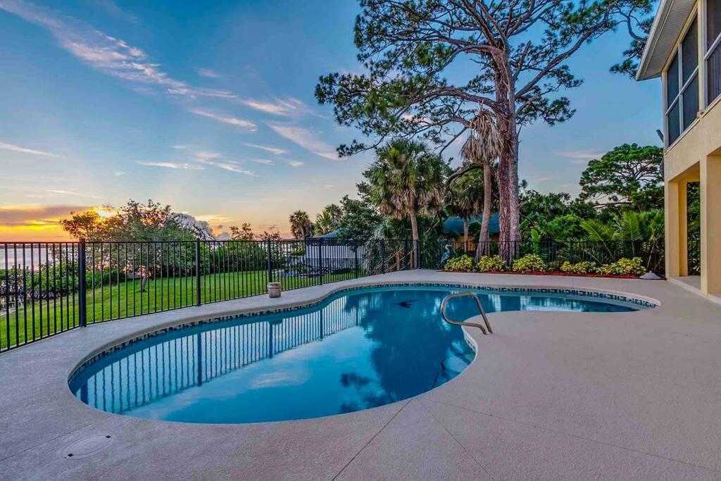 a swimming pool in a yard with a fence at Tropical Riverfront Paradise - Gorgeous Sunset Views in Merritt Island