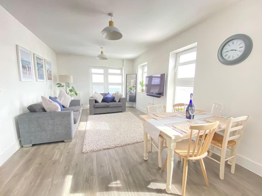 a living room with a table and chairs and a clock at Stunning 2 bed, water front Poole Quay Apartment. in Hamworthy