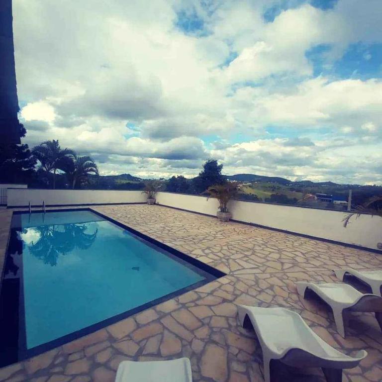 ein Pool mit zwei weißen Stühlen daneben in der Unterkunft Jardim Secreto in Serra Negra