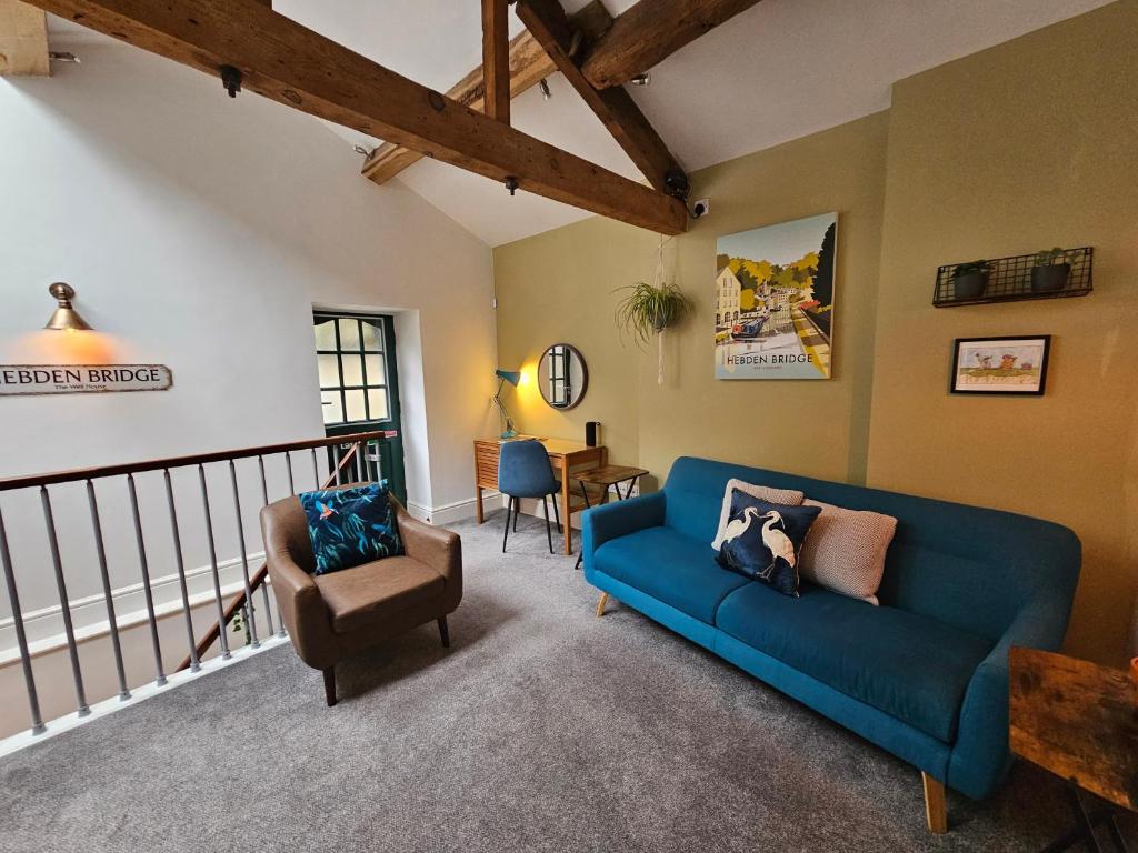 a living room with a blue couch and a chair at The Well House Boutique Cottage Hebden Bridge Central in Hebden Bridge
