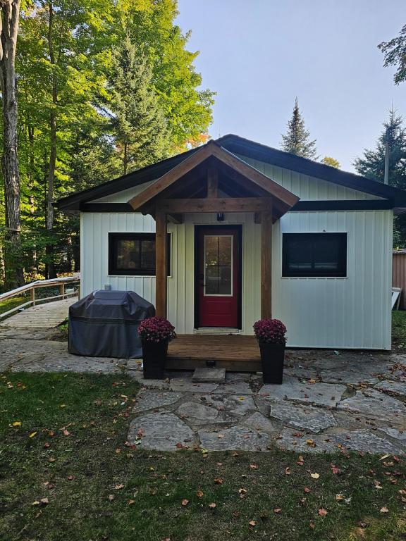 a tiny house with a red door in a yard at Bearfoot Bungalow in Sauble Beach