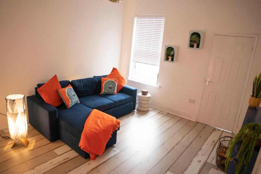 sala de estar con sofá azul y almohadas de color naranja en Sara’s Apartment, en Seaham