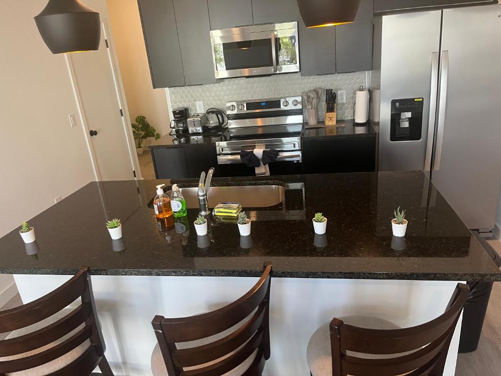 a kitchen with a black counter top with chairs at Brand New Townhouse, min from Disney in Kissimmee
