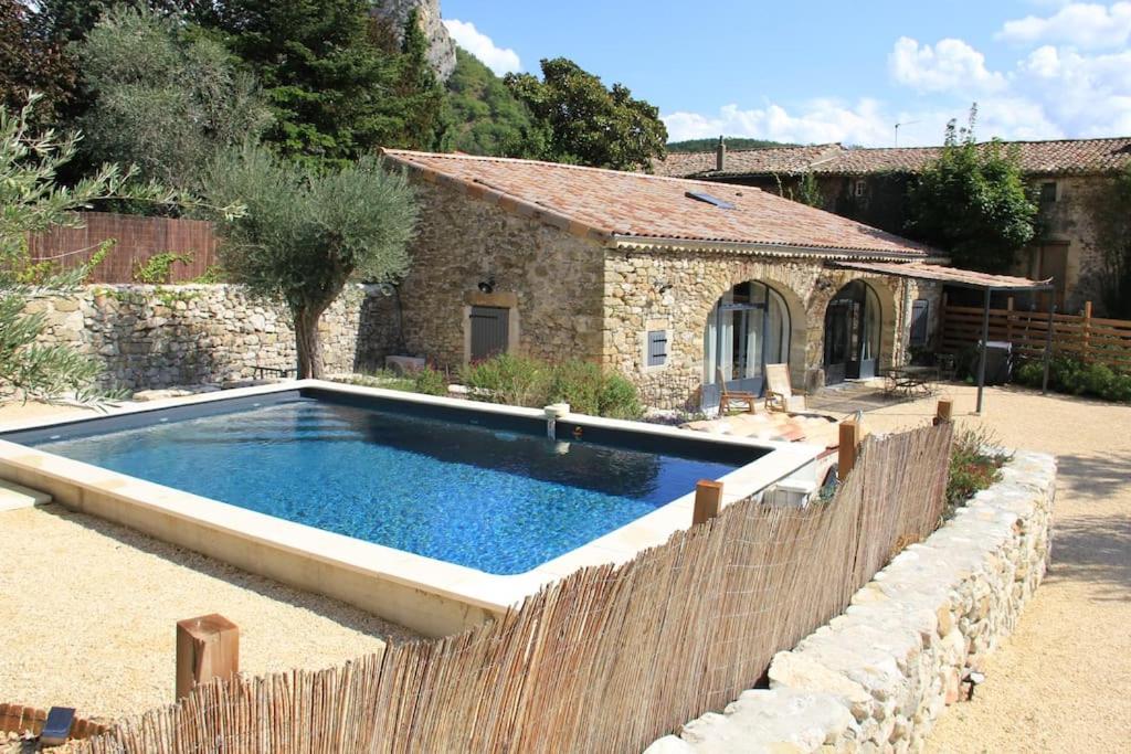 una piscina frente a una casa de piedra en Gîte Les Oliviers, en Saou