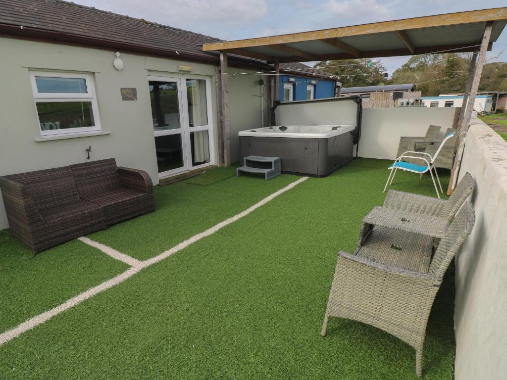 een patio met groen gras en een bad en stoelen bij Meadow View in Laugharne