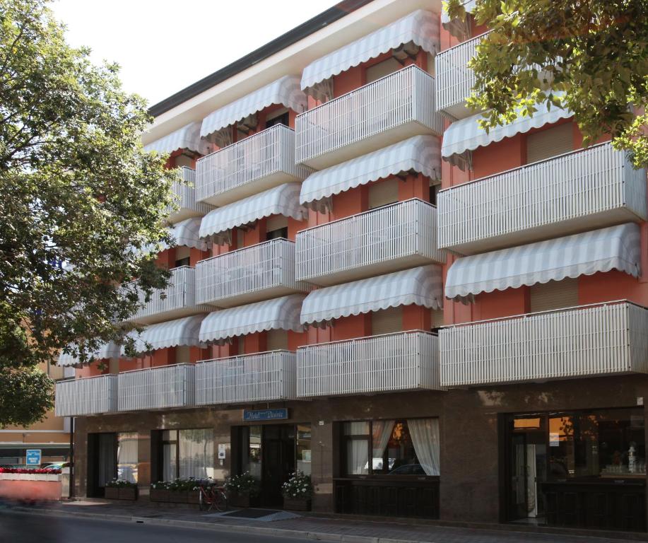 un edificio de apartamentos con balcones blancos en una calle en Hotel Desiree, en Lignano Sabbiadoro