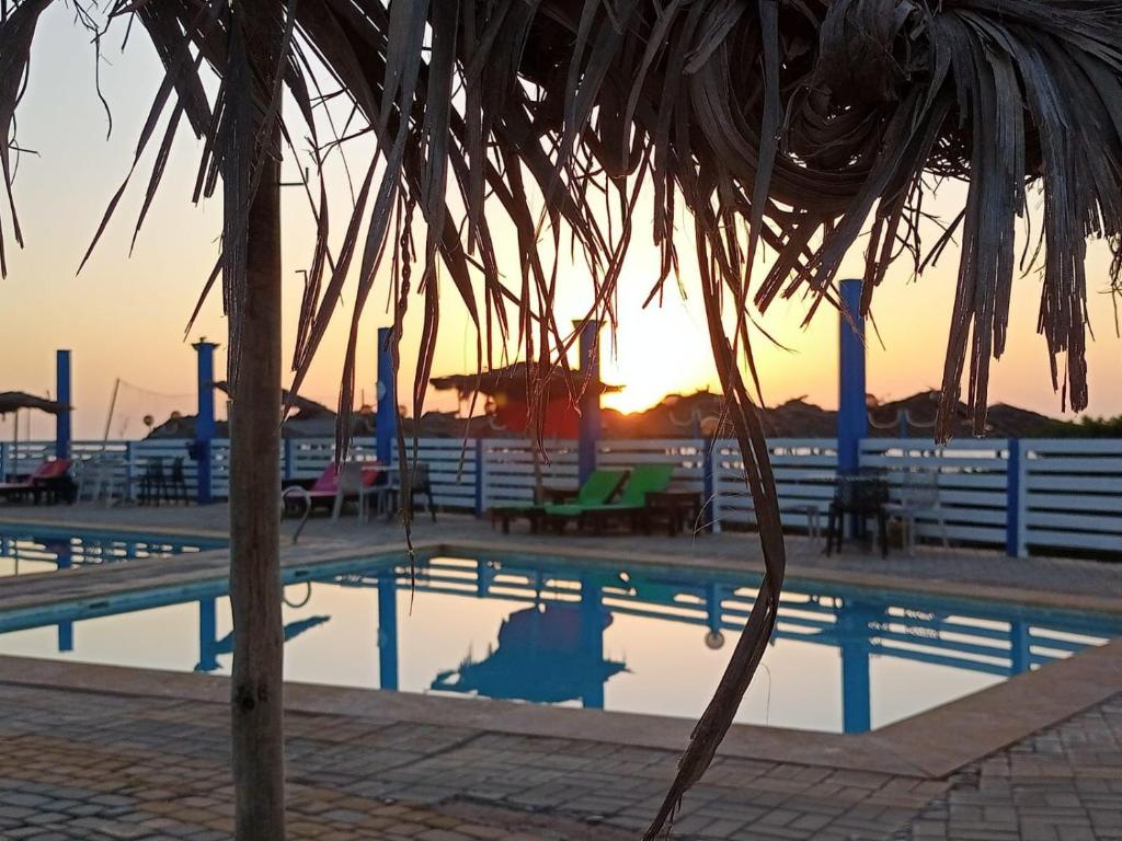 ein Resortpool mit Sonnenuntergang im Hintergrund in der Unterkunft Kasbah lagzira in Sidi Borja