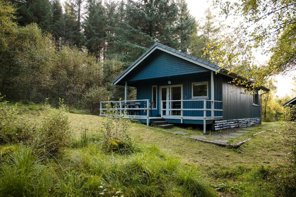 a blue cottage in the middle of a field at Otter chalet in Crianlarich