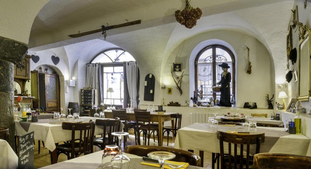 a restaurant with tables and chairs and two windows at Hotel Pascal in Allos