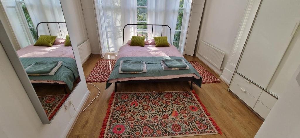 two beds in a small room with a rug at Primrose Hill - Charming, Cosy, 2 Double Bedrooms Apartment in London