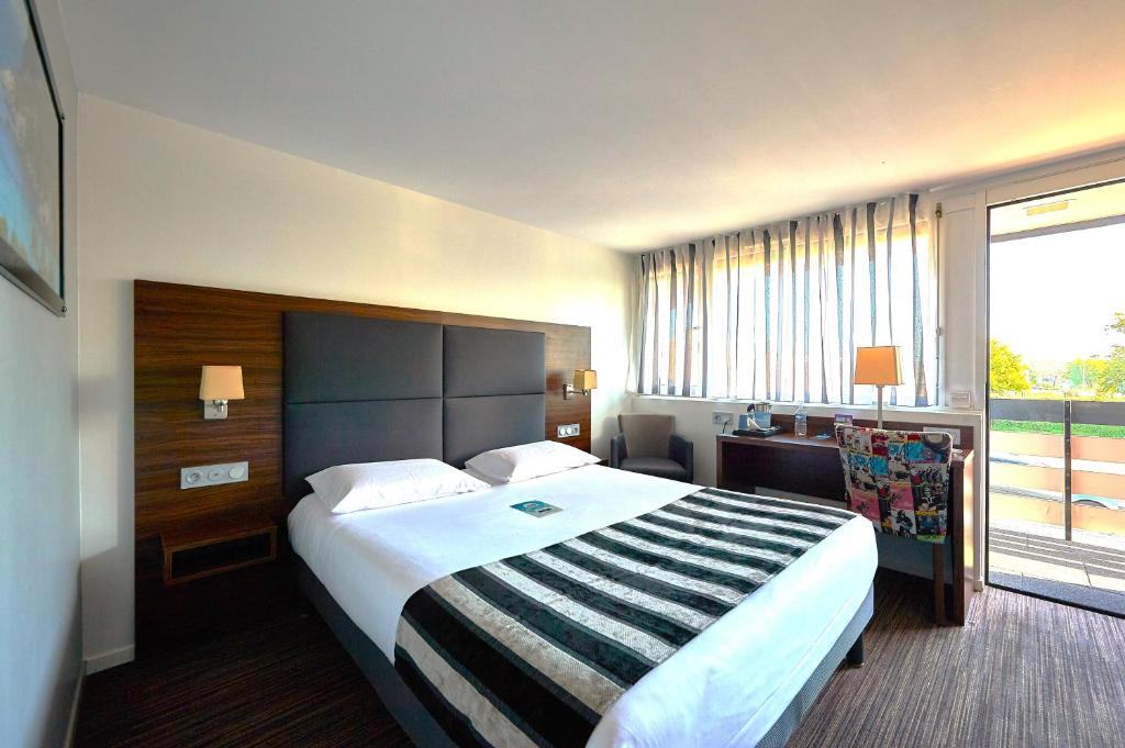 Una habitación de hotel con una cama grande y una ventana. en Kyriad Bordeaux - Merignac Aéroport, en Mérignac