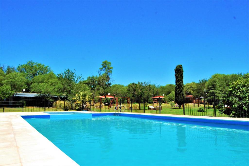 une piscine bleue avec une aire de jeux en arrière-plan dans l'établissement Keantúpa Cabañas, à San Marcos Sierras