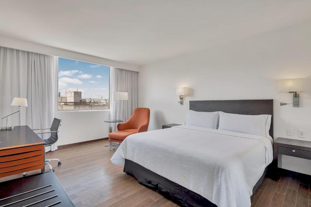 A king bedroom with a dedicated desk, lounge chair and city view.