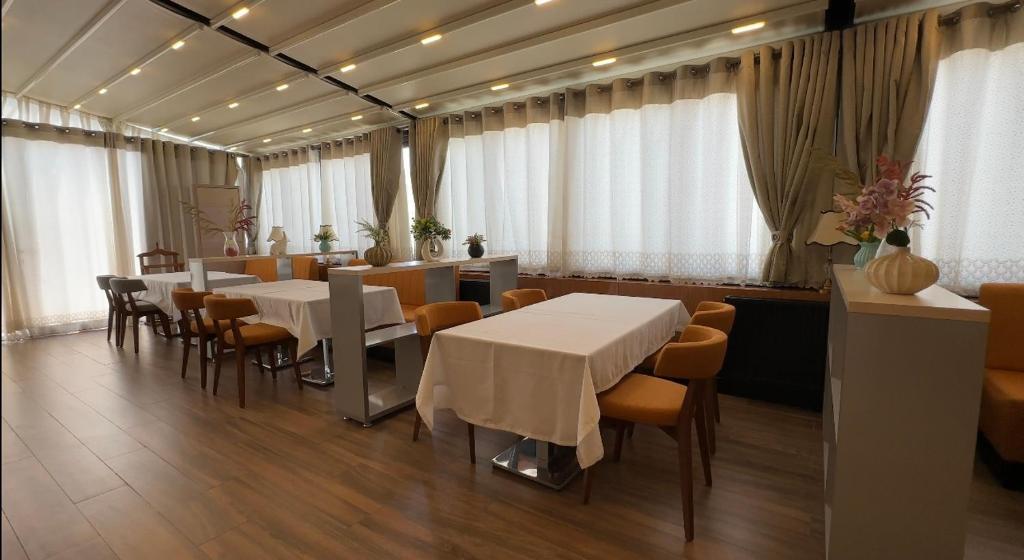 布哈拉的住宿－Hotel Bukhara，一间设有白色桌椅的用餐室