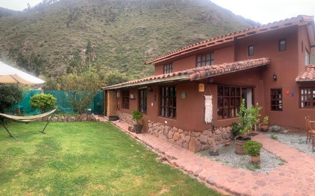 een huis met een tuin en een berg op de achtergrond bij Habitacion en Casa de Campo, Valle Sagrado de los Incas in La Planicie