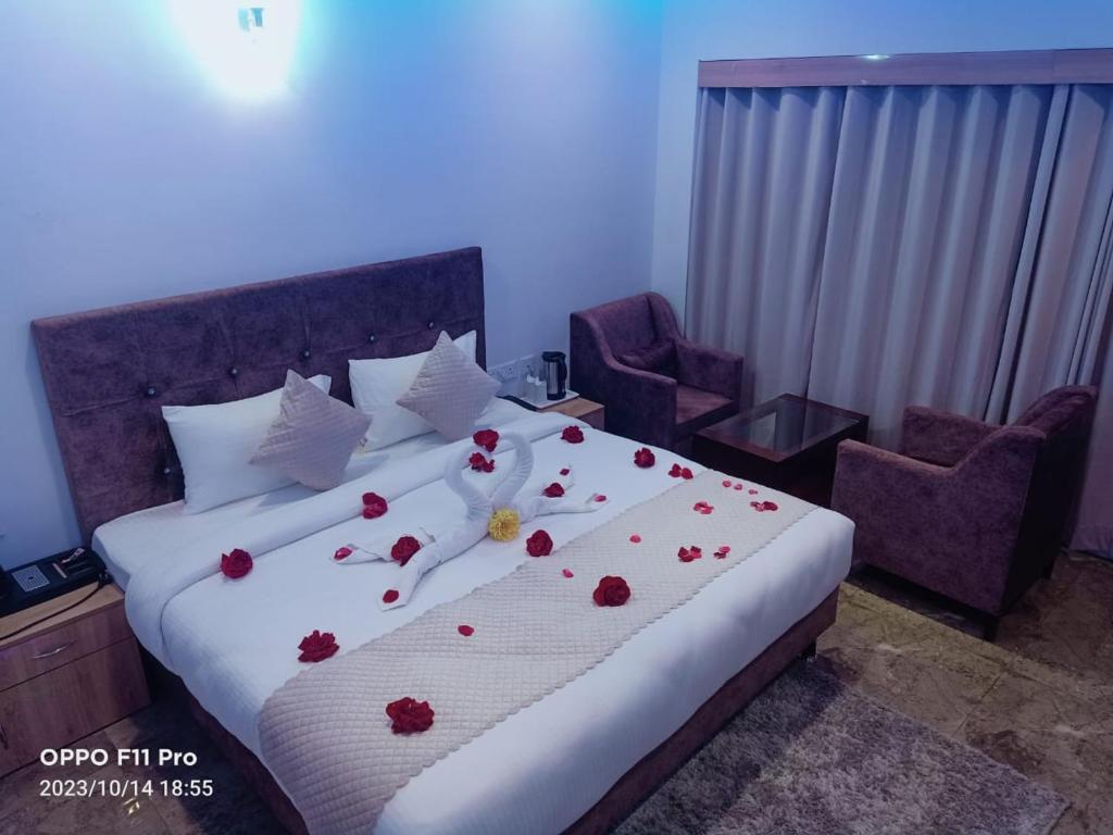 Hotel candlewood Shimla في شيملا: غرفة نوم مع سرير مع زهور حمراء عليه