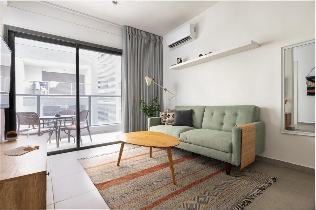 a living room with a green couch and a table at Family Apartment By IsrApart in Ramat Gan
