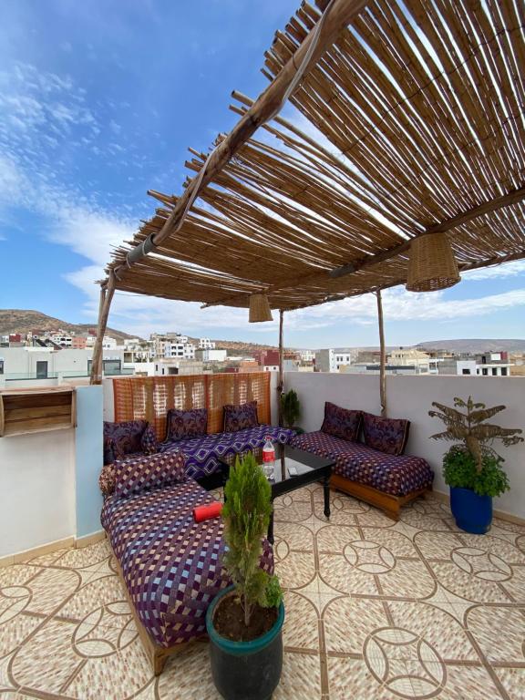 un patio con sofá y una mesa en el techo en Atlas Surf Morocco, en Tamraght Ouzdar
