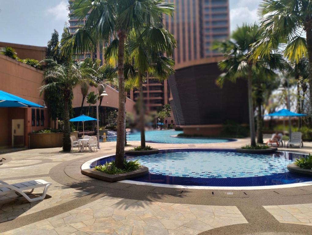 a swimming pool with palm trees in a courtyard at Times Square Service Suites Kuala Lumpur in Kuala Lumpur