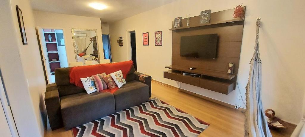 uma sala de estar com um sofá e uma televisão em APTO BELA VITA AO LADO VINÍCOLA AURORA em Bento Gonçalves