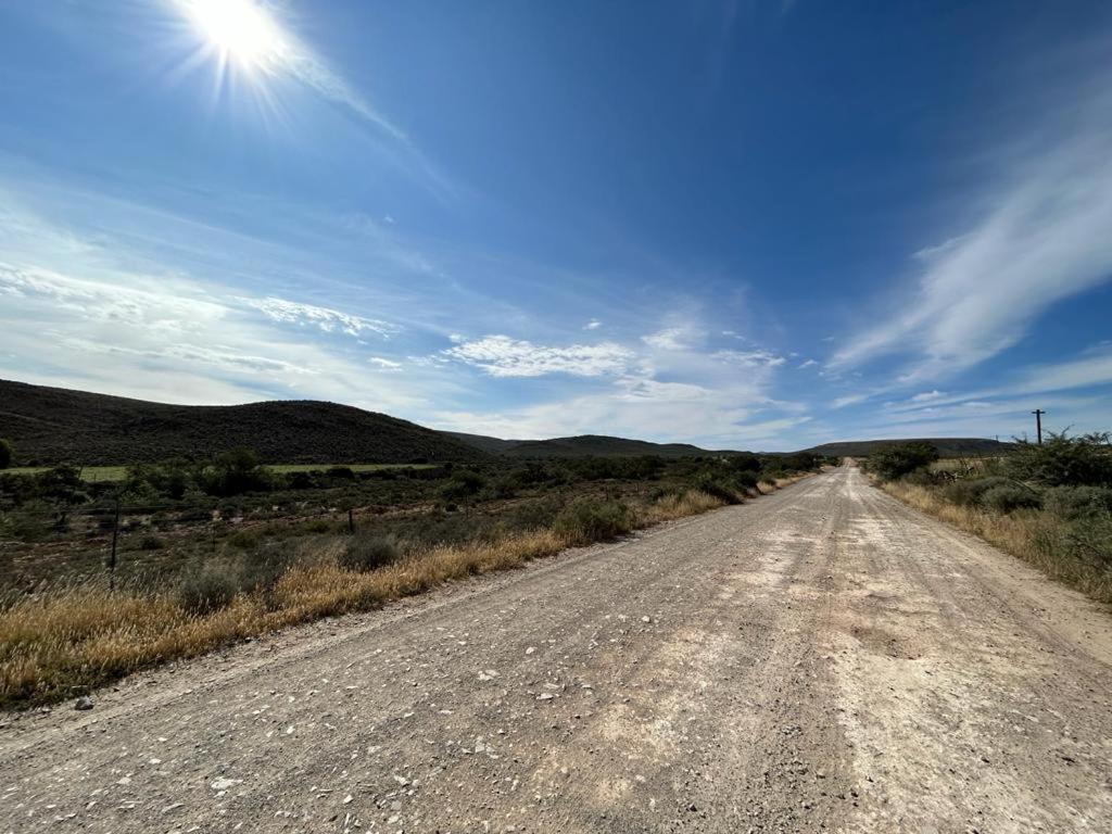 an empty road in the middle of a field at Vaalwater Lodge & Bush Camp in Willowmore