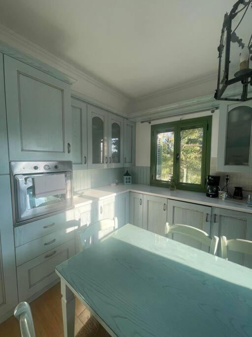 a kitchen with white cabinets and a table and chairs at La nymphe Aegina in Áyioi Asómatoi