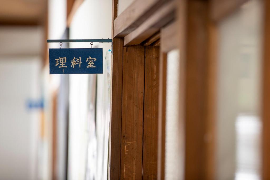 una señal azul colgando de una puerta de madera en Mori no Bunkou Fuzawa - Vacation STAY 86824v en Kobayashi