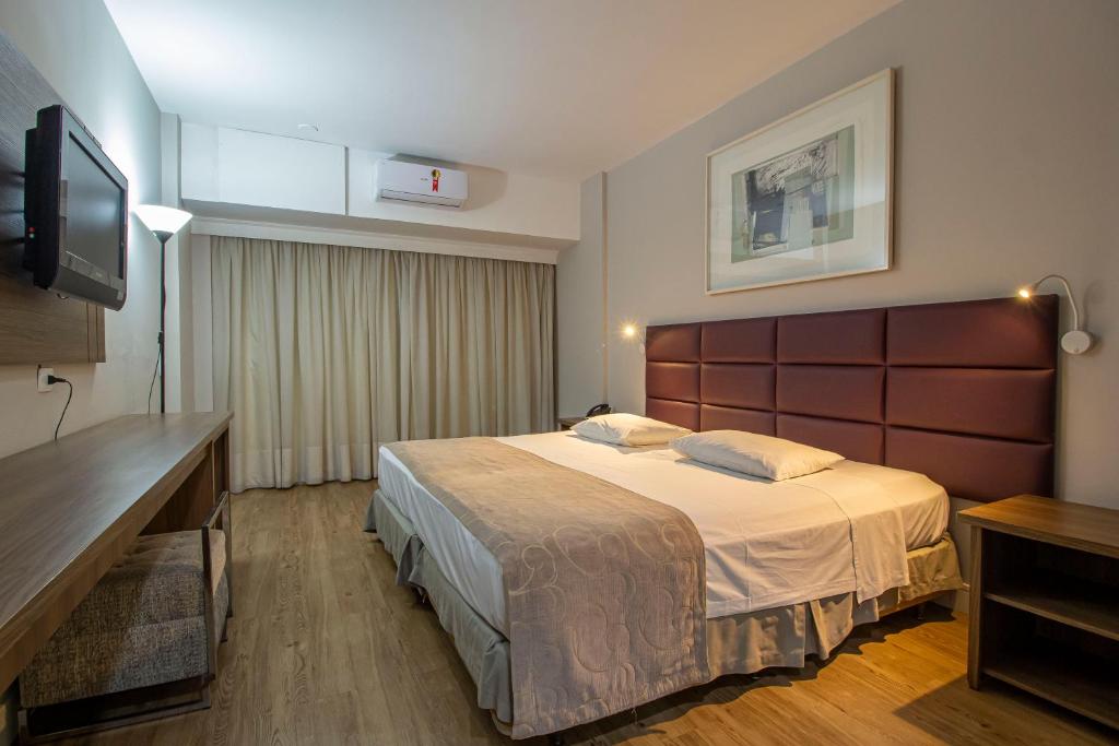 um quarto de hotel com uma cama e uma televisão de ecrã plano em Hotel Victoria Villa Curitiba by Nacional Inn em Curitiba