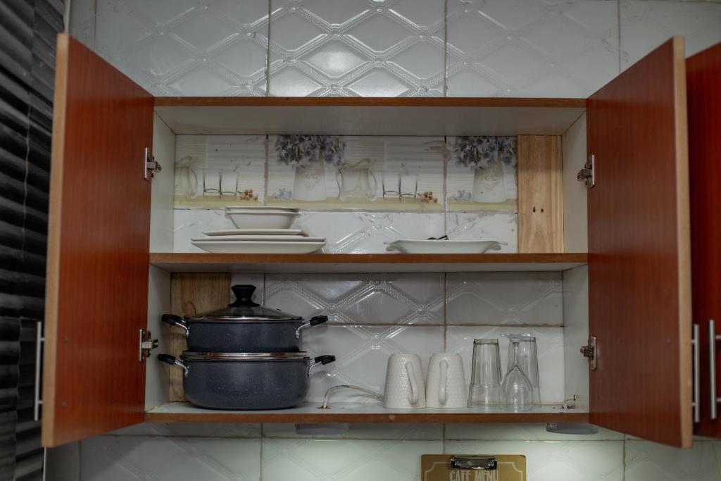 a cabinet with a pot and dishes in it at Mars cozy apartment in Dar es Salaam