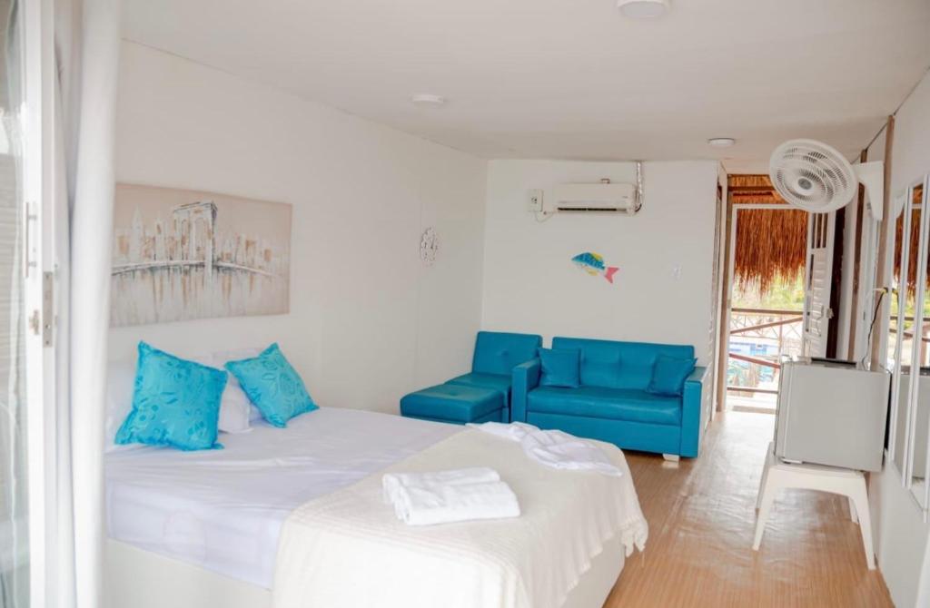 a white room with a bed and a blue couch at Estadía en hermoso hotel en la isla de punta arena cartagena in Playa Punta Arena