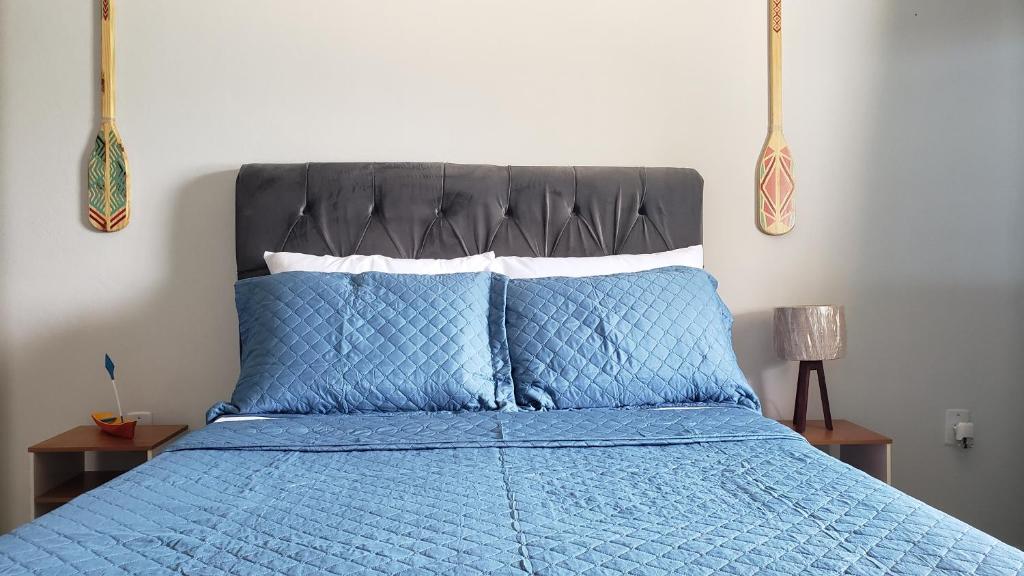 uma cama com um edredão azul e almofadas azuis em Encanto do Mar em Praia de Araçatiba
