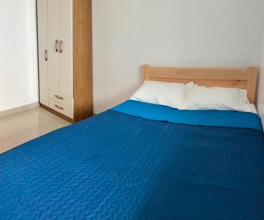 Schlafzimmer mit einem blauen Bett und einem Kopfteil aus Holz in der Unterkunft Airbnb Paracas Inn in Pisco