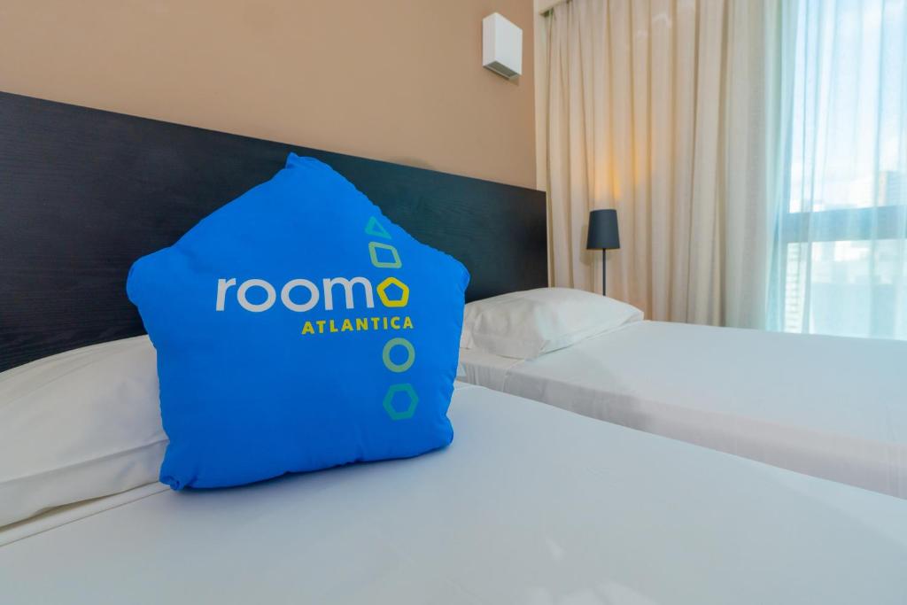 a hotel room with a blue pillow on a bed at Roomo Praia de Boa Viagem Residencial in Recife