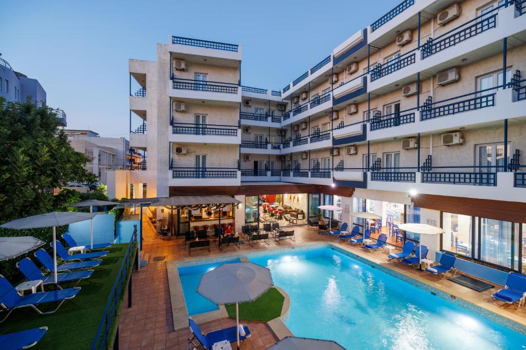 una piscina de hotel con sillas y sombrillas frente a un edificio en Agrabella Hotel, en Hersonissos