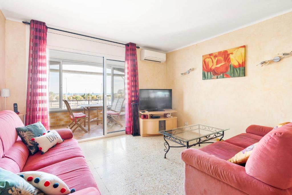 ein Wohnzimmer mit einem rosa Sofa und einem TV in der Unterkunft Apartamento WELCS EMP-096- con vistas al canal in Empuriabrava