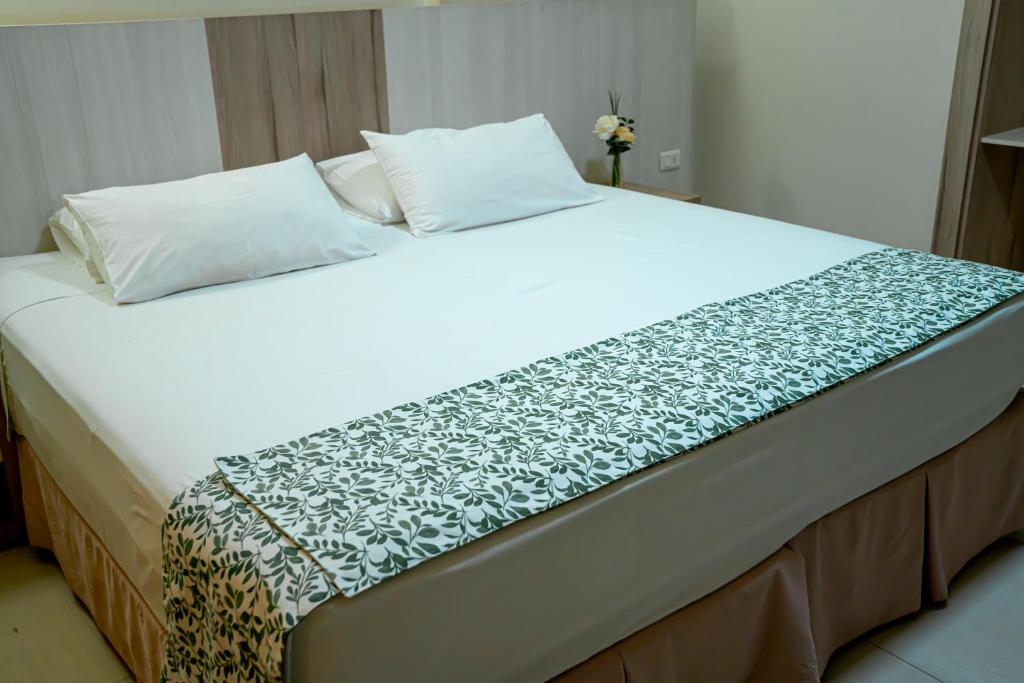 a large white bed with a black and white blanket at Megal Suites Hotel in Ciudad del Este