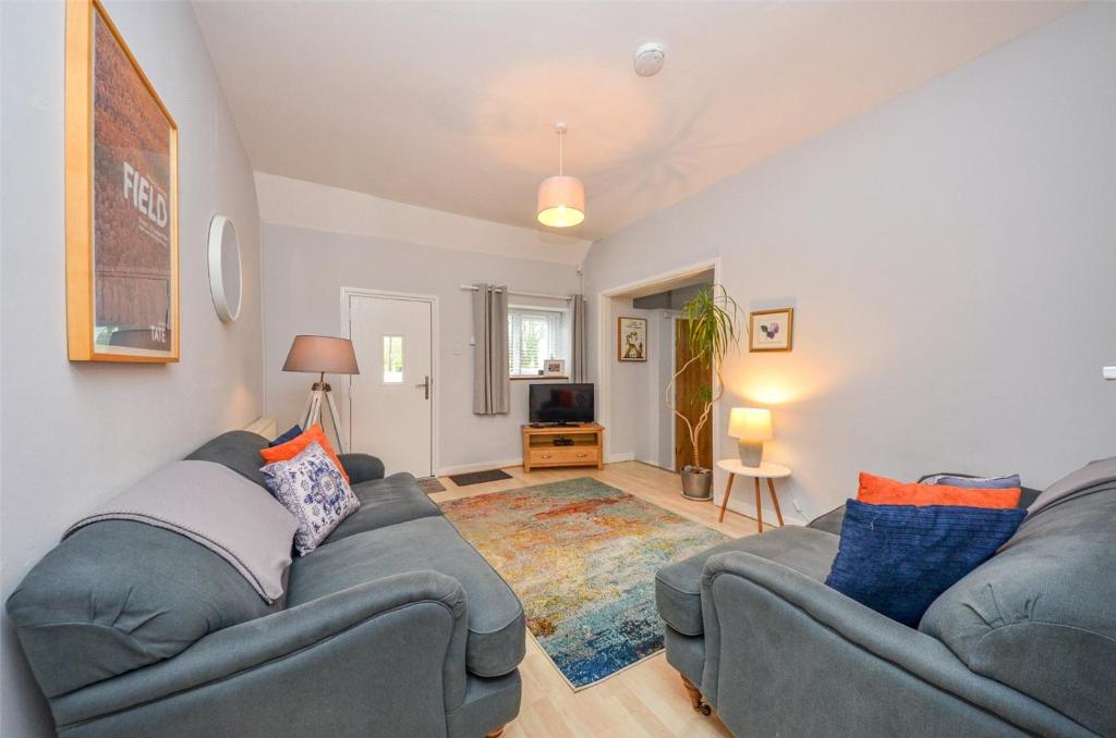 a living room with two couches and a television at Gwyllt Cottages in Dwyran