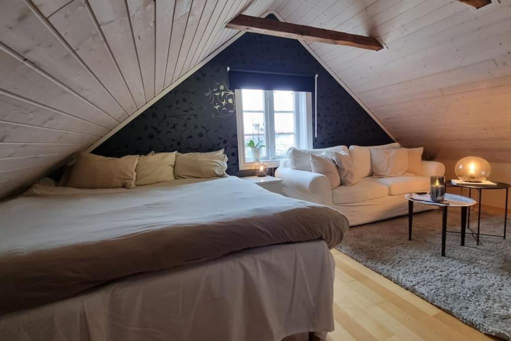 a bedroom with a bed and a couch in a attic at Central villa med extra allt. Pool, Bastu, Utekök in Kalmar