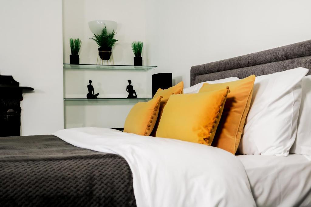 1 dormitorio con 1 cama con almohadas amarillas y blancas en Boutique 2 Bedroom Apartment In Pontcanna Cardiff en Cardiff