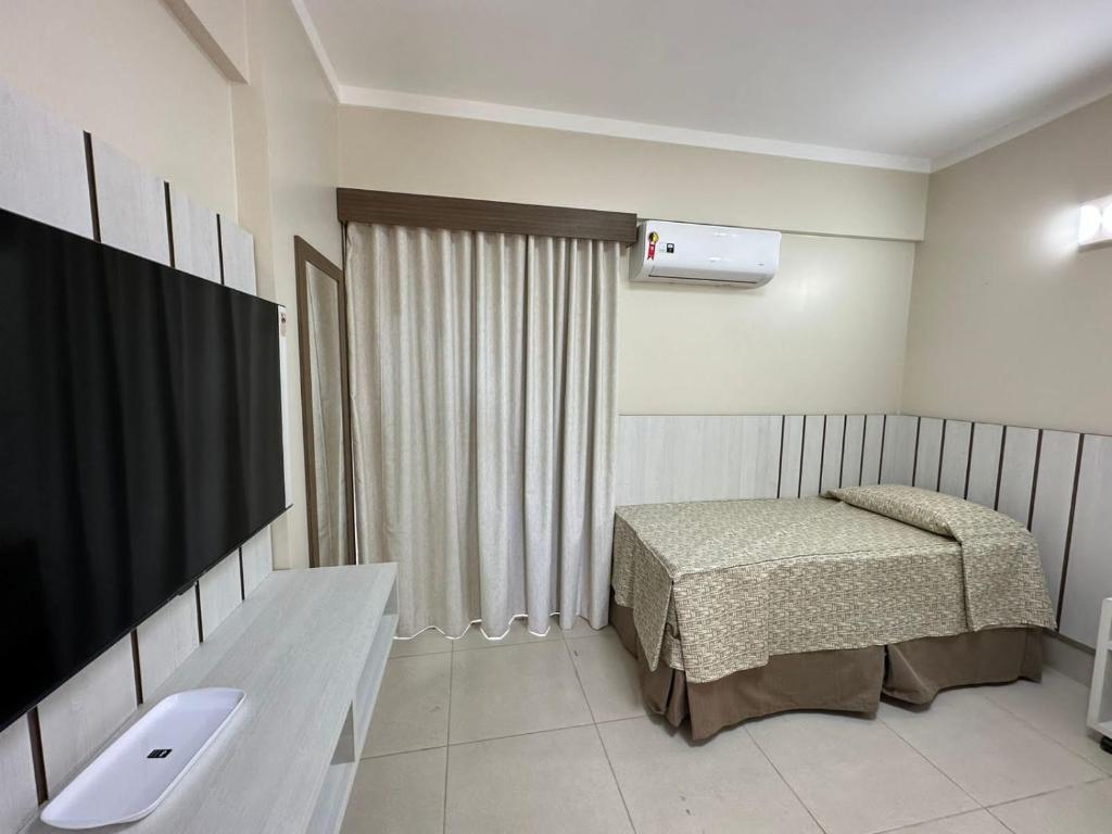 Zimmer mit einem Bett und einem TV. in der Unterkunft Spazzio diRoma 2024 - COM CAFÉ DA MANHÃ in Caldas Novas