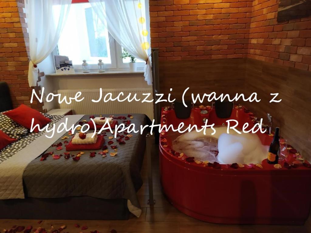 a room with a tub with a bed and a window at Jacuzzi Apartment Red in Krakow