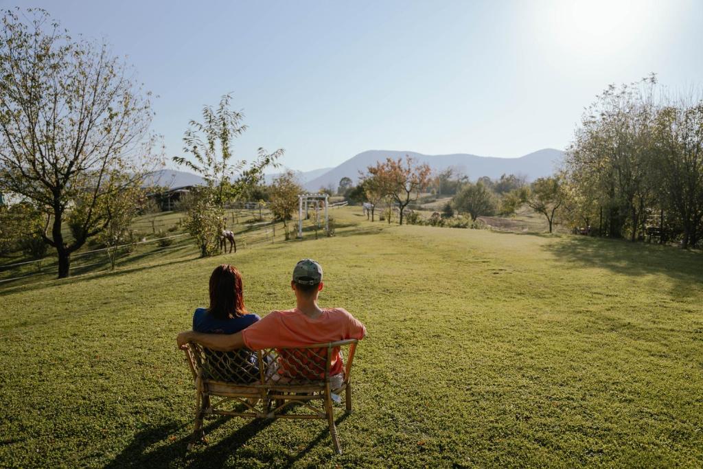 Un uomo e una donna seduti su una panchina in un campo di Ranch Terra a Irinovac