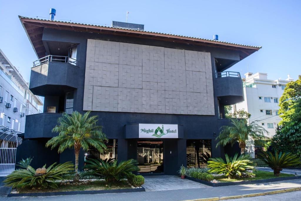 un bâtiment avec des palmiers en face de celui-ci dans l'établissement Mighil Hotel & Eventos, à Florianópolis