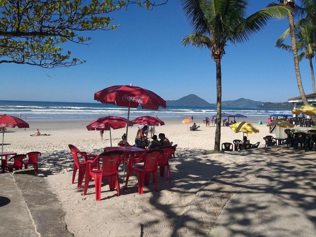 pessoas sentadas em mesas na praia sob guarda-sóis em Apartamento com piscina churrasqueira em Ubatuba em Ubatuba