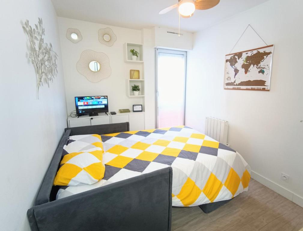 - une chambre avec un lit et une couette jaune et blanche dans l'établissement Jolie studio cosy à 2 pas du centre-ville, à Montpellier