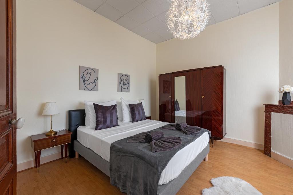 a bedroom with a large bed and a chandelier at La Maison du Repos Toulouse Purpan in Toulouse