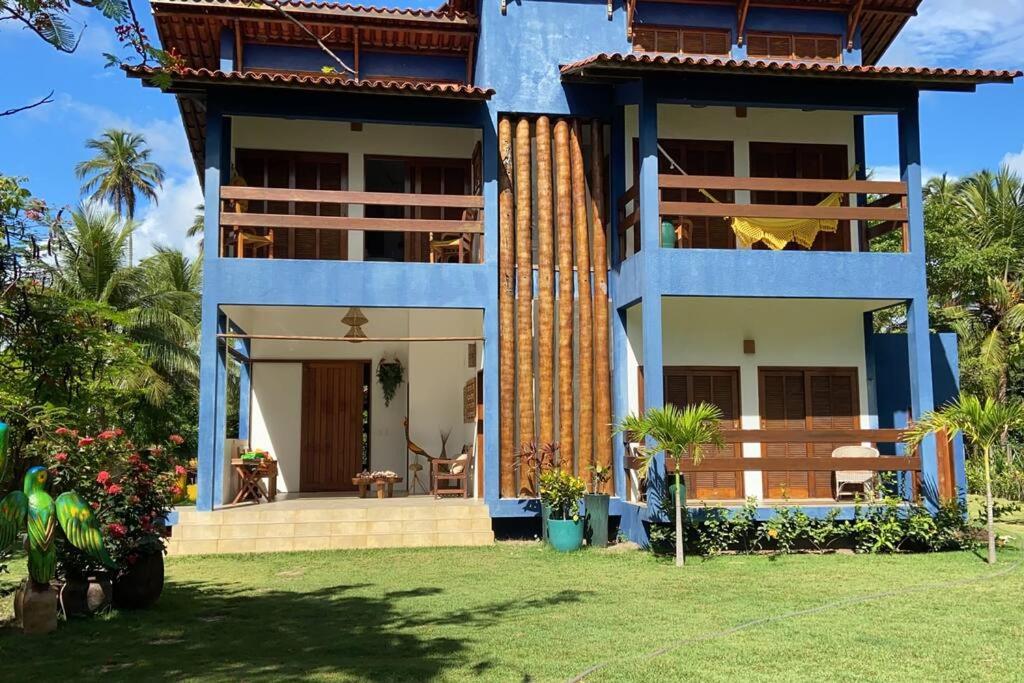 a house with a blue facade with a yard at Maravilhoso chalé num paraíso em Japaratinga in Japaratinga